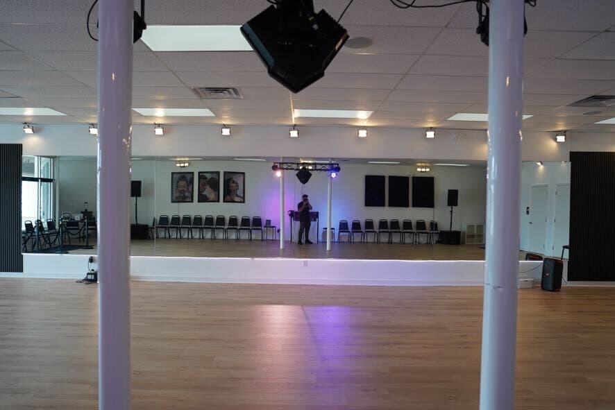 The mirror wall reflecting the stage lighting truss and the far side of the room