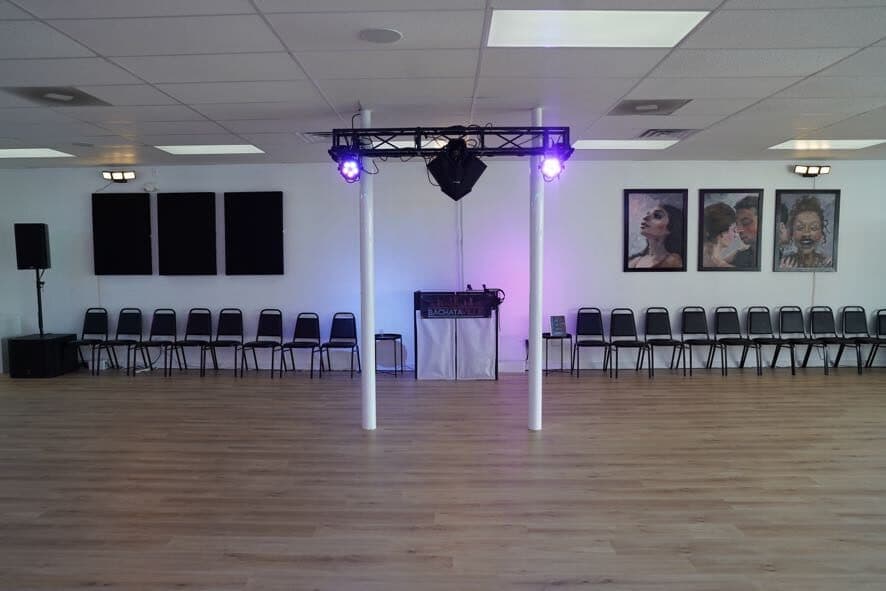 DJ booth under a lighting truss with speakers and chairs on either side